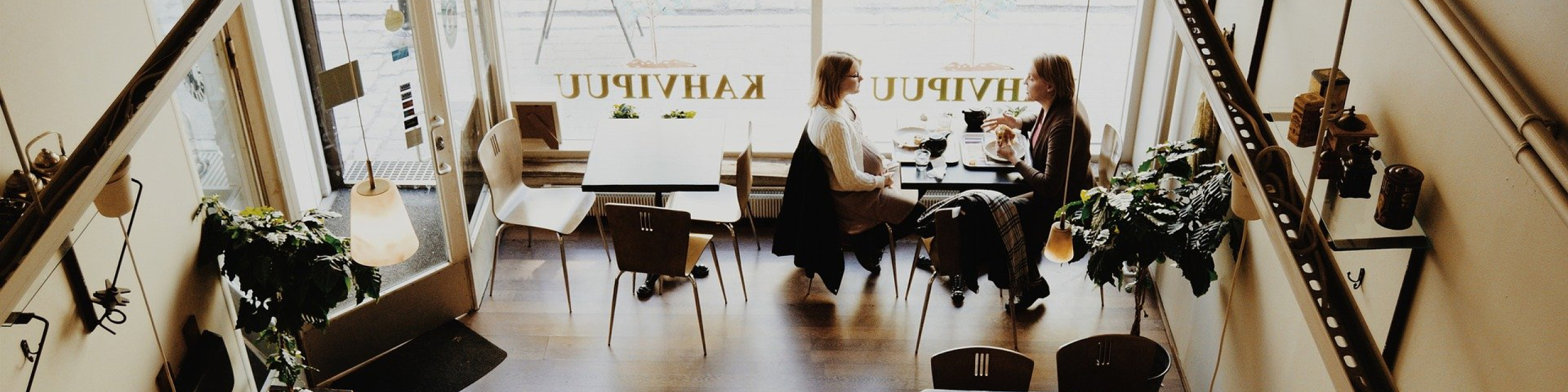 窓際のテーブルに女性二人が座っている店内を上から撮った写真